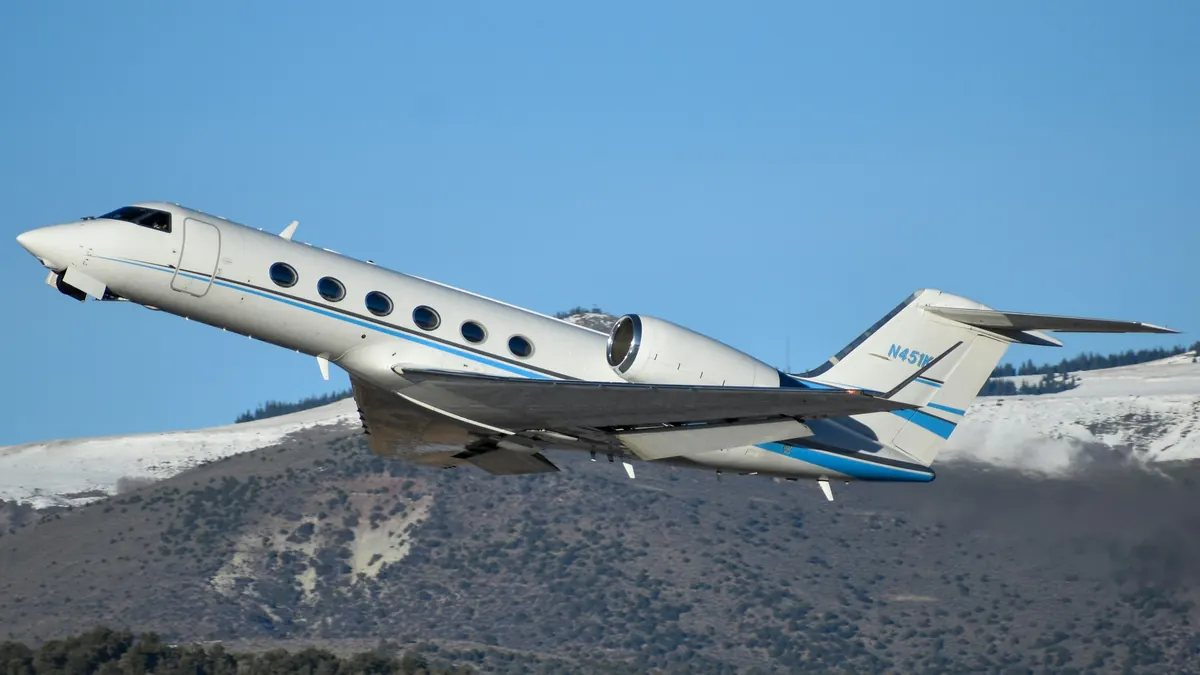 Gulfstream jet climbing past snow-covered mountains
